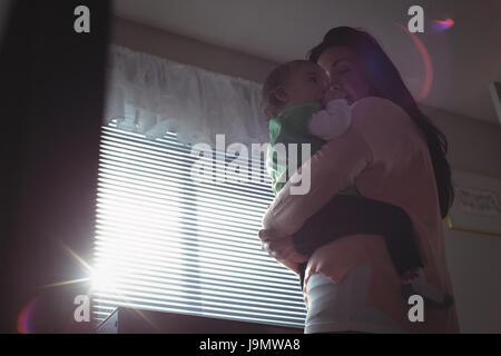 Affettuosa madre che porta il suo bambino in camera da letto a casa Foto Stock