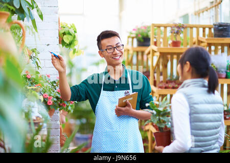 Giovani asiatici fioraio maschio hanno la conversazione con il cliente in negozio Foto Stock