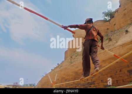 Un circo bambino camminare e bilanciamento sulla corda usando un lungo bastone Foto Stock