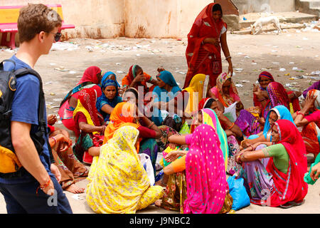 Uno straniero che passa dal lato di un gruppo di donne di Rajasthani nei tradizionali abiti colorati e dicendo namaste (ciao) Foto Stock