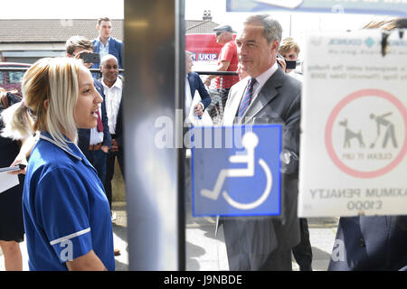 Un dipendente di una farmacia parla dell ex leader dell'UKIP Nigel Farage come egli fa una campagna elettorale visita a Tilbury, Essex. Foto Stock