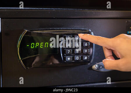 Mano premere il tasto su nero cassetta di sicurezza con lo stato aperto Foto Stock