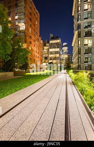 Highline promenade e vecchi binari ferroviari al crepuscolo con alta aumenta e la costruzione di luci in Chelsea. Manhattan, New York City Foto Stock