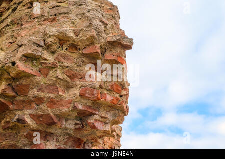 Le antiche rovine della distrutta e rotture di un muro di mattoni di fortezza contro lo sfondo del cielo per il background testurizzata Foto Stock