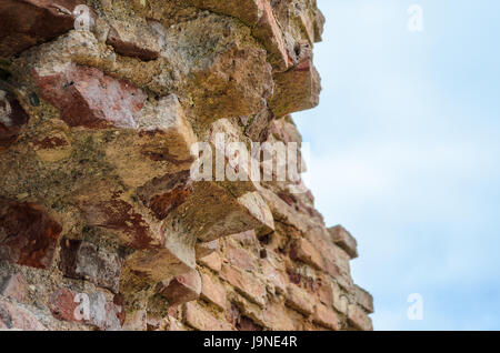 Le antiche rovine della distrutta e rotture di un muro di mattoni di fortezza contro lo sfondo del cielo per il background testurizzata Foto Stock