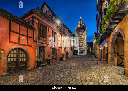 Sera street con Dolder Tower e colorato tradizionali tipiche case a graticcio in Riquewihr villaggio sul vino alsaziano route, Alsazia, Francia Foto Stock