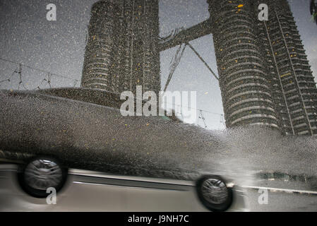 Petronas Towers si vede nella riflessione di una pozza in strada. Kuala Lumpur, Malesia. Foto Stock