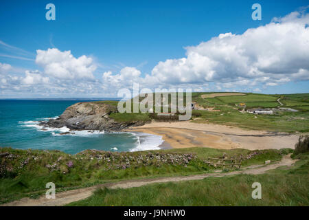 Una veduta della chiesa cove, Cornwall, una larga spiaggia di sabbia ingresso circondato da scogliere e campi verdi sotto cumulus cloud su una bella giornata Foto Stock