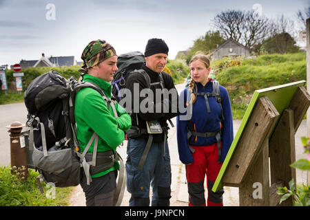 Nel Regno Unito, in Galles, Pembrokeshire, St Davids, tre giovani visitatori vestiti per camminare guardando information board a Oriel y Parc, galleria e centro visitatori Foto Stock