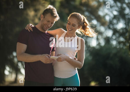 Basso angolo vista di felice coppia giovane utilizzando il telefono cellulare sulla giornata di sole Foto Stock