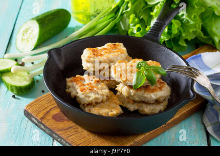 Fettine di carne a partire da carni macinate, servita in una ghisa padella con fagiolini e tavolo da cucina in stile rustico. Foto Stock