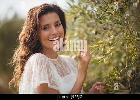 Close up ritratto di felice giovane donna spiumatura olive presso l'azienda Foto Stock