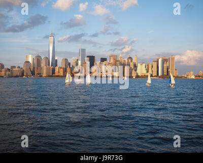 J24 barche a vela vela sul fiume Hudson con la vista dello skyline di New York City e nuvole sopra Manhattan Battery Park City aka la batteria Foto Stock