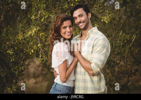 Ritratto di amorevole coppia giovane in piedi da alberi di olivo agriturismo Foto Stock