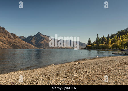 Queenstown, Nuova Zelanda - 15 Marzo 2017: Guardando ad ovest dal centro di Riva mostra secco, desolata , Marrone montagne attraverso il profondo blu del lago Wakatipu, s Foto Stock