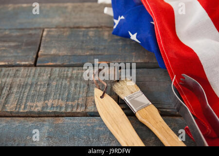 Pennello e tong con bandiera americana disposta sul tavolo in legno Foto Stock
