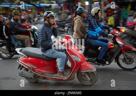 L'uomo sul cellulare scooter di equitazione su strade trafficate, il vecchio quartiere di Hanoi, Vietnam Foto Stock