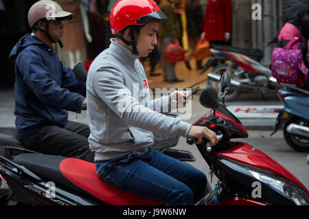 L'uomo sul cellulare in sella scooter, il vecchio quartiere di Hanoi, Vietnam Foto Stock