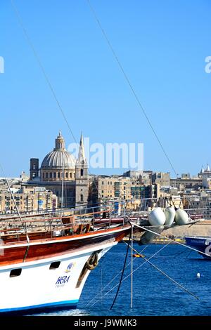Vista di St Pauls Cattedrale Anglicana e la Basilica di Nostra Signora del Monte Carmelo con una barca in primo piano si vede attraverso il Grand Harbour da Sli Foto Stock