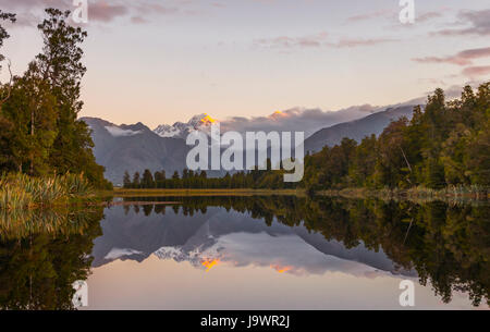 Sunset, Specchio Isola, Mt. Tasman e Mt. Cuocere, riflesso nel lago Matheson, parco nazionale di Mount Cook, Westland National Park Foto Stock