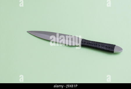 Coltello per il lancio di nero con un avvolgimento di una maniglia. Su uno sfondo verde chiaro. Foto Stock