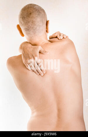 L'uomo massaggiare il suo top back, il muscolo trapezius, a causa di una vertebra toracica il dolore a causa lo spostamento di una vertebra dorsale sfregamento su un nervo Foto Stock