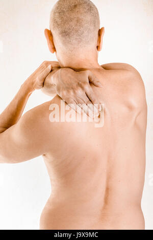 L'uomo massaggiare il suo top back, il muscolo trapezius, a causa di una vertebra toracica il dolore a causa lo spostamento di una vertebra dorsale sfregamento su un nervo Foto Stock