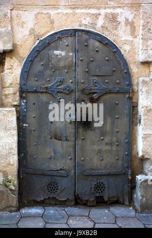 Antica porta di metallo nel muro di pietra della vecchia casa. Foto Stock