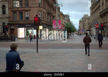 Ragazzo adolescente seduto da solo in una strada dello shopping di notte Buchanan St, Glasgow Foto Stock