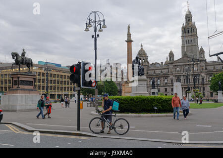 Deliveroo Uber bikers consegna i driver per i ciclisti su strada per somministrare a Glasgow Foto Stock