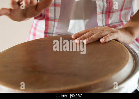 Capretto che gioca il tamburo Djembe, primo piano, concentrarsi sulla mano che si posa sulla membrana dello strumento Foto Stock