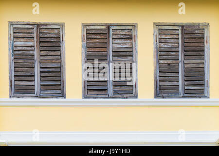 Vecchia finestra di legno marrone sul muro di cemento Cino-portoghese architettura di stile a Phuket Thailandia - possono essere utilizzate per la visualizzazione o montaggi sul prodotto Foto Stock