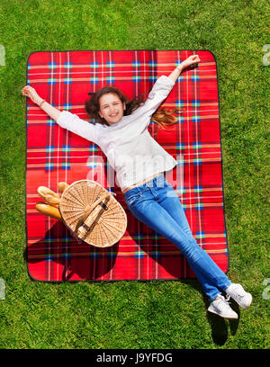 Ragazza rilassante sul prato erboso accanto al cesto a mano Foto Stock