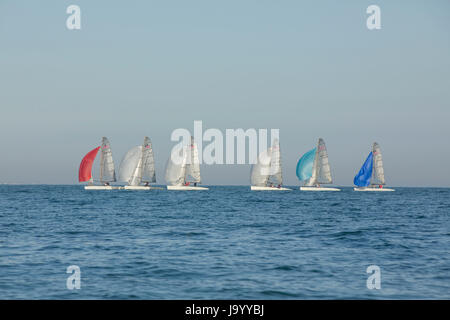 Gruppo di barche a vela di preparazione alla gara su una soleggiata sera primaverile all'ingresso al porto di Chichester Hayling Island. Formare una fila ordinata. Foto Stock