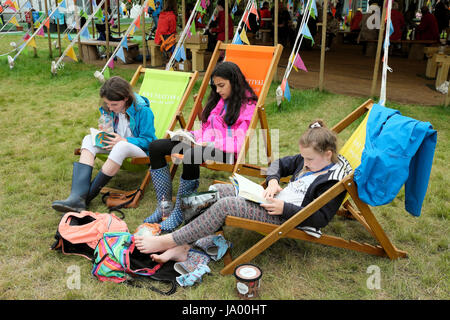 Un gruppo di ragazze adolescenti amici leggere libri seduti su sedie a sdraio sul fieno sito del Festival Hay-on-Wye, Wales UK KATHY DEWITT Foto Stock