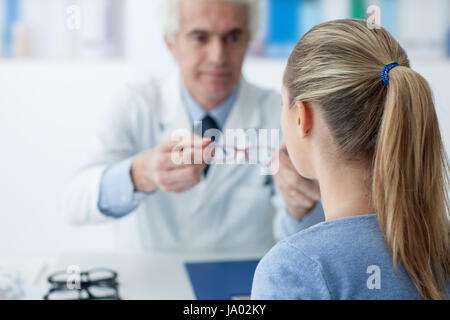 Ottico maschio dando nuovi occhiali al paziente dopo la visita, la sanità e la cura degli occhi concept Foto Stock