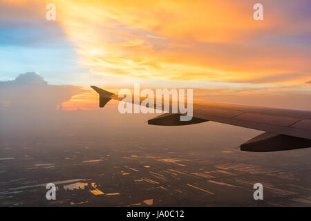 Tramonto in Twilight time con ala di un aeroplano e cloud sky. Foto applicata al turismo operatori. immagine per aggiungere messaggio di testo o il sito web di telaio. Tra Foto Stock