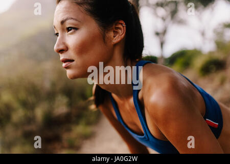 Close up della giovane donna asiatica in appoggio dopo allenamento e guardando lontano. Femminile in sportswear prendendo una pausa. Foto Stock