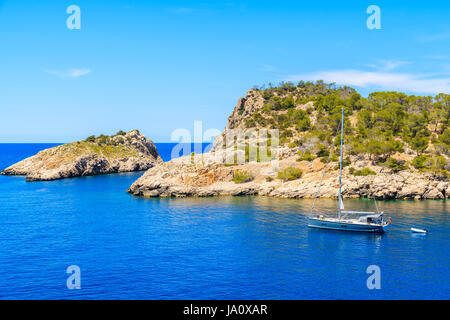 Barca a vela sul blu dell'acqua di mare a Cala Salada bay, isola di Ibiza, Spagna Foto Stock