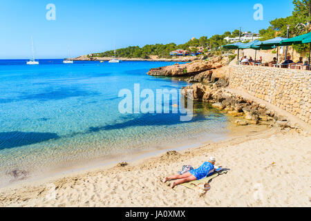 CALA PORTINATX, isola di Ibiza - Maggio 22, 2017: donna posa sulla spiaggia e la lettura di libro in Cala Portinatx bay sull isola di Ibiza, Spagna. Foto Stock