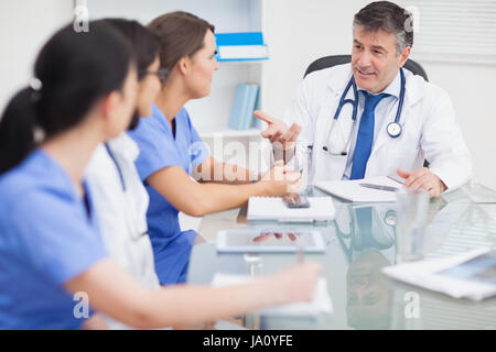 Incontro tra un medico e tre infermieri e un medico sorridente in ufficio Foto Stock