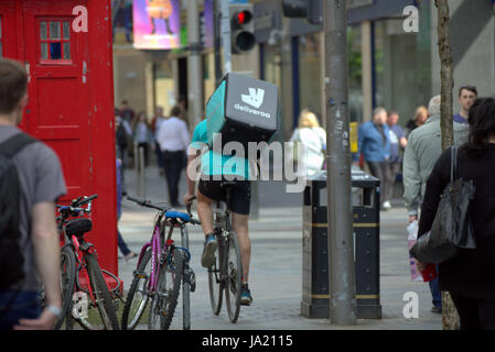 Deliveroo Uber bikers consegna i driver per i ciclisti su strada per somministrare a Glasgow Foto Stock