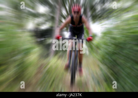 Sfocata dello Sport. Mountain Bike ciclista in sella singola traccia e il ciclista in sella a una moto su un fuori strada al tramonto Foto Stock