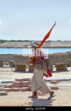 Vetical cattura di una religiosa uomo indù holyman passeggiate, portando una bandiera dal suo pellegrinaggio al tempio di Krishna a Dwarka in Gujarat India Febbraio 27 2103 Foto Stock