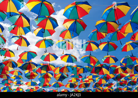 Ombrelloni colorati sfondo. Coloruful ombrelloni strada urbana decorazione. Appendere ombrelloni multicolori oltre il cielo blu Foto Stock