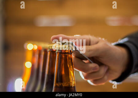 Close up di un uomo con un assolcatore per le bottiglie di birra artigianale su sfondo sfocato Foto Stock