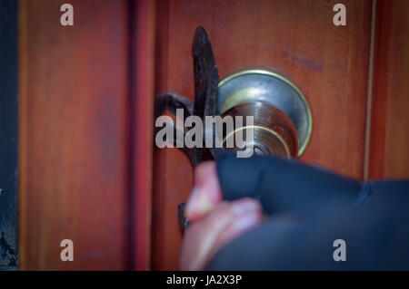 Close up di un ladro con crowbar cercando sfondare la porta per entrare nella casa Foto Stock