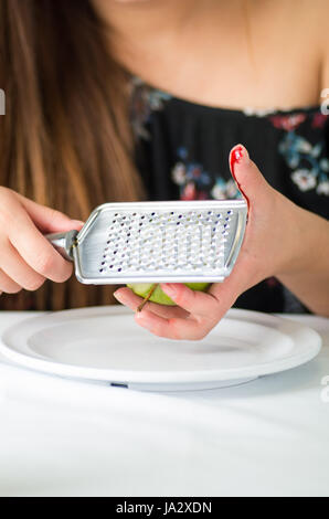 In prossimità di una donna ferita a mano il suo dito utilizzando un reticolo nella piastra da cucina Foto Stock