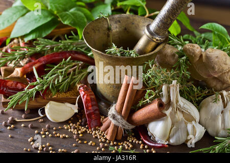 Diverse erbe e spezie su di un tavolo di legno . Rame antico mortaio con spezie . Foto Stock