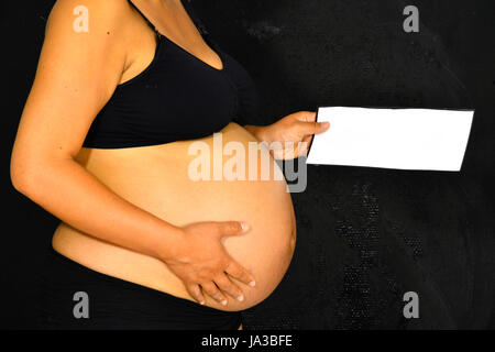 Una donna in stato di gravidanza con in mano una nota con una stanza per il testo. Foto Stock